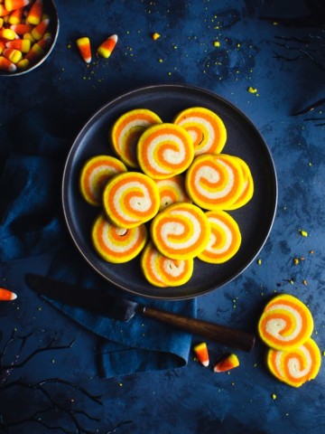 plate of candy corn cookies with candy corn, other cookies and a knife around the edges