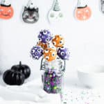 straight on shot of cake pops in a jar with halloween decorations in the background