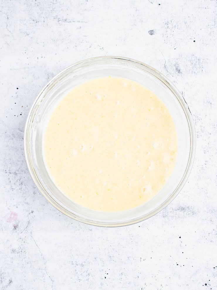 Overhead view of lemon cupcake batter in a clear bowl.