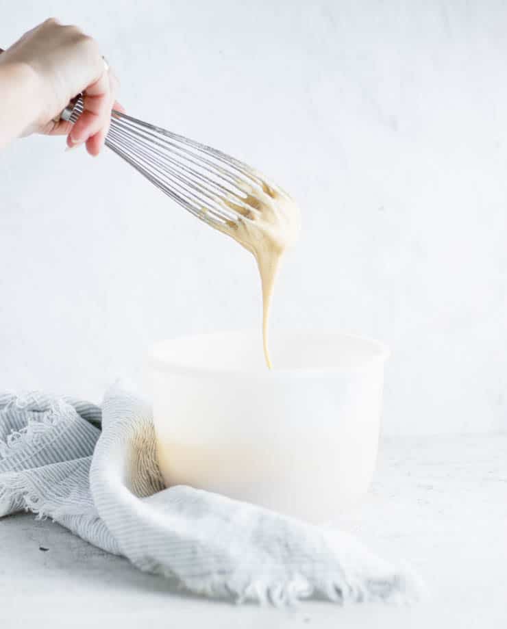 batter dripping off of a whisk into a bowl