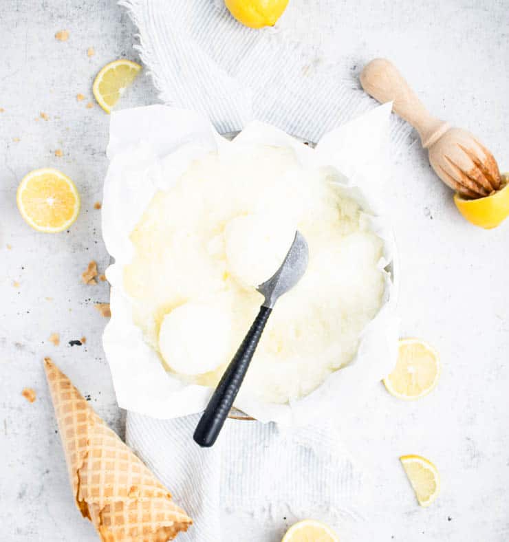 lemon sorbet in a cake pan with ice cream cones and lemons around it.