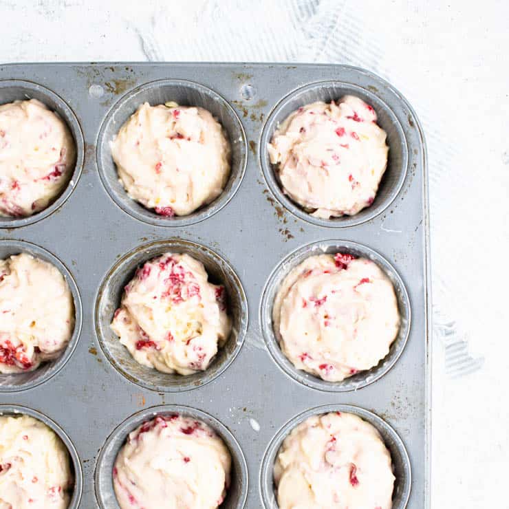 raspberry muffin batter in a muffin pan.