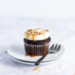 frosted cupcake on top of two plates with a fork