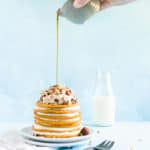 pouring maple syrup on a stack of cream cheese filled pancakes