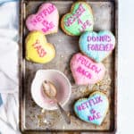 heart shaped pop tarts scattered around a baking tray with an empty bowl of frosting in the middle
