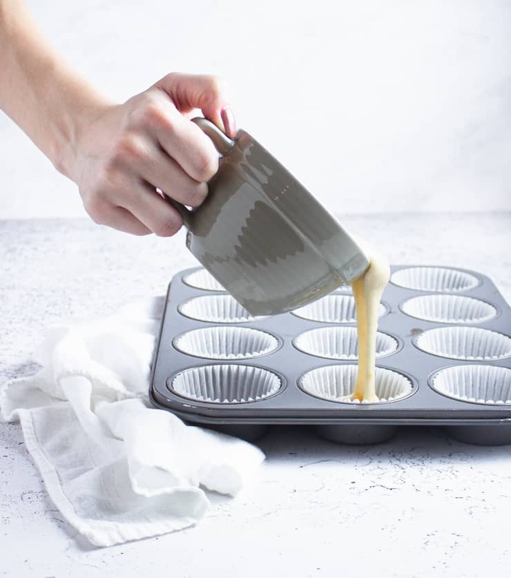 pouring cake batter into a cupcake pan