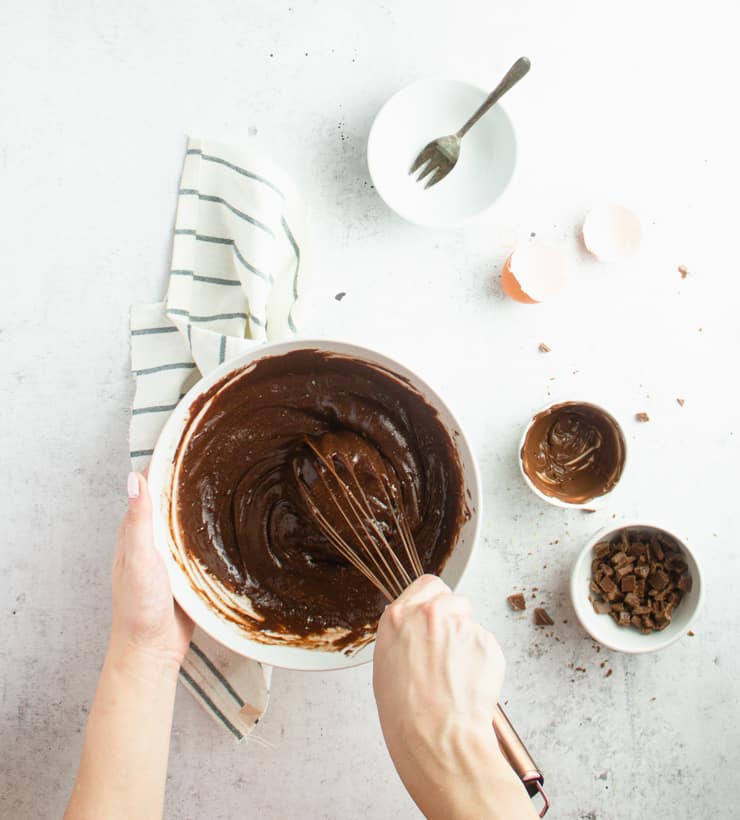 hands stirring brownie batter with a whisk