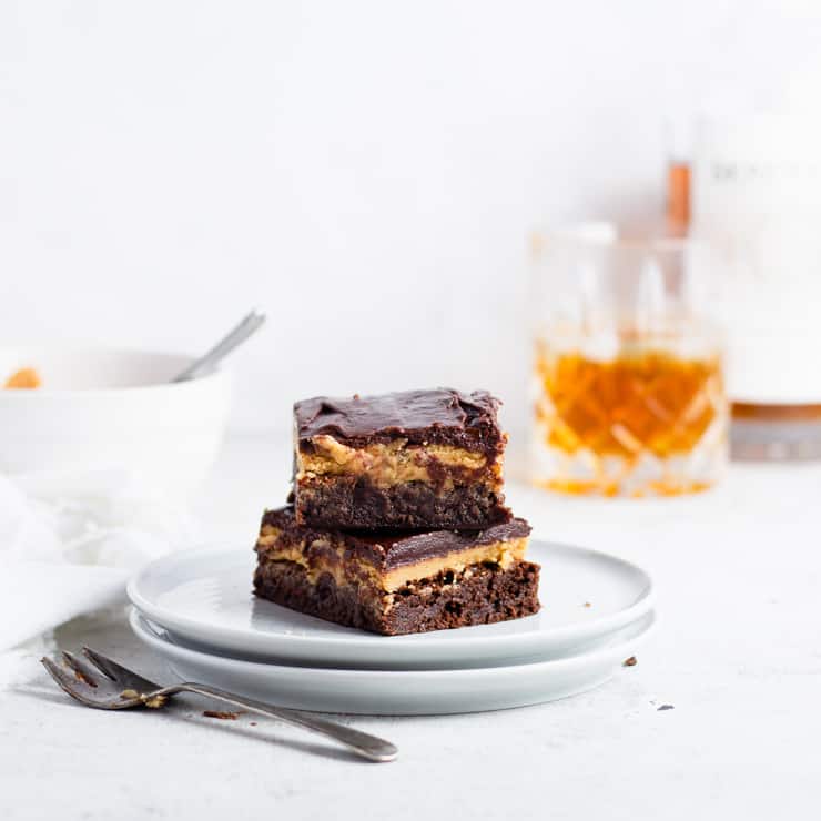 stack of brownies on a plate with drink and bowl in background