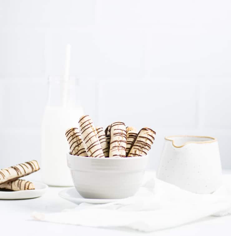 almond cookies in a bowl with a pitcher and glass of milk in the background