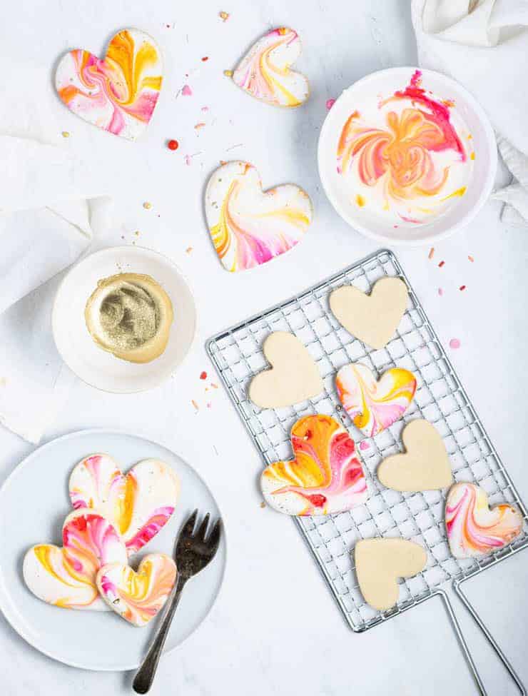 iced valentine cookies on a cooling rack with a bowl of icing next to them