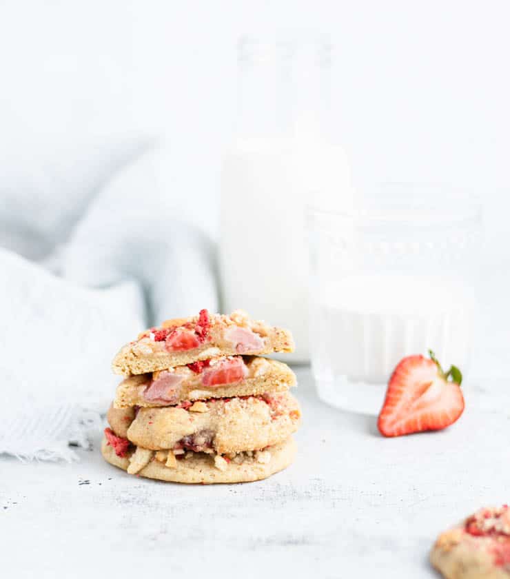 stack of strawberry cookies next to a glass of milk.