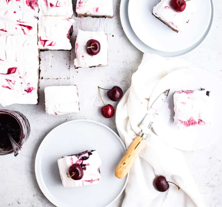 overhead view of sliced cheesecake on plates topped with cherries.