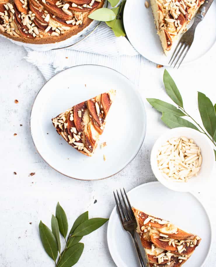 triangular slices of apple cake on blue plates with green foliage around it.