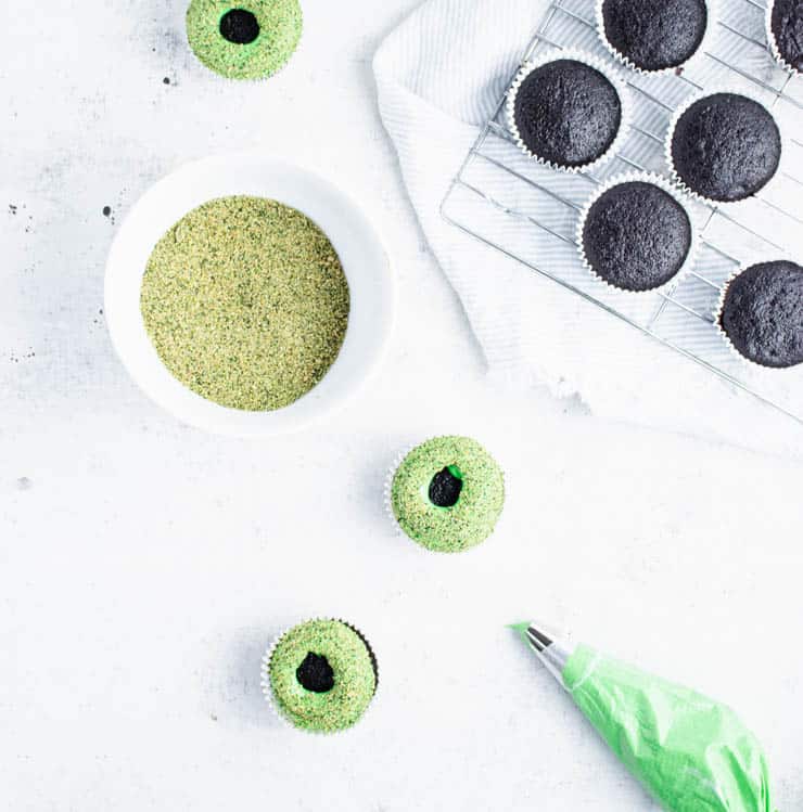 green frosted cupcakes topped with crushed green graham cracker crumbs on a white backdrop.