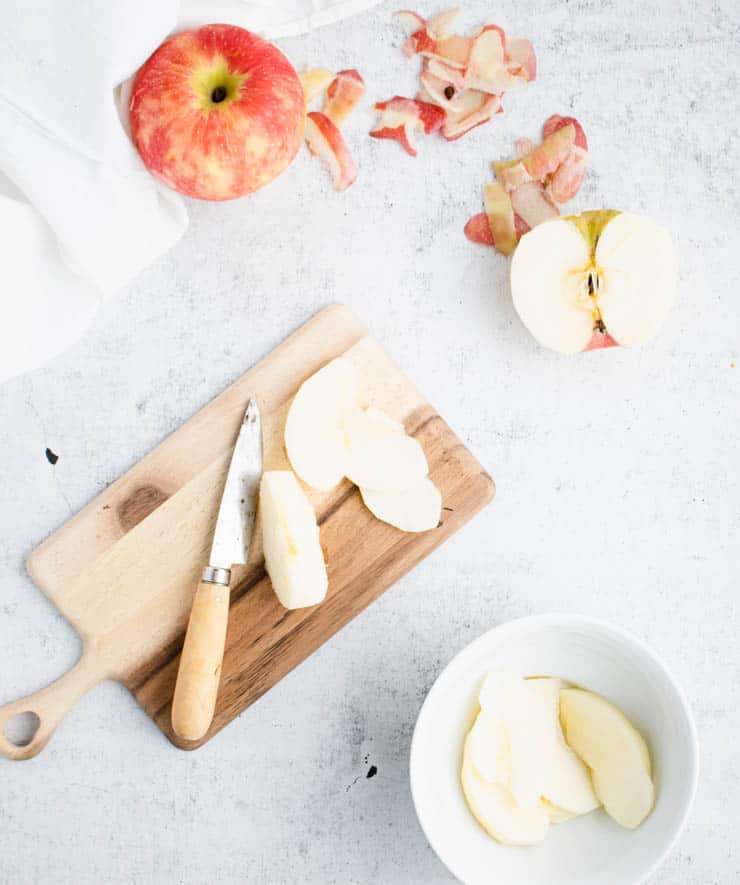 sliced apples on a cutting board with a small paring knife.