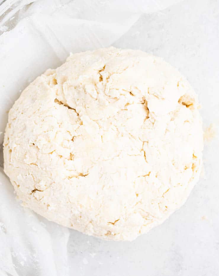 Close up of a rough dough with a few cracks and bits of visible butter.