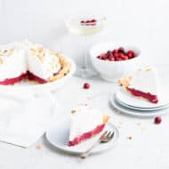 Close up of a slice of cranberry pie showing the bright red curd filling and the toasted meringue topping.