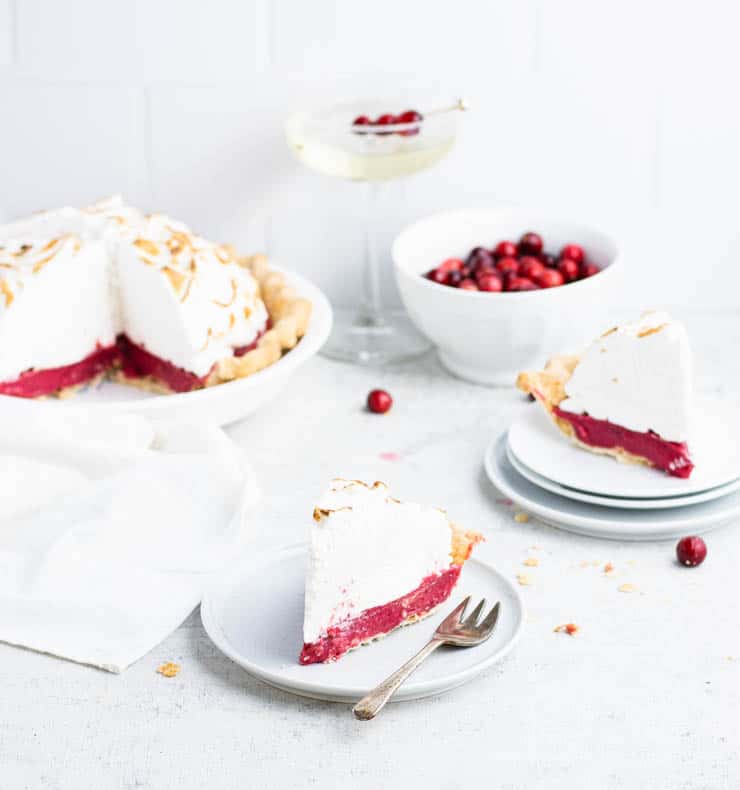 Close up of a slice of cranberry pie showing the bright red curd filling and the toasted meringue topping.