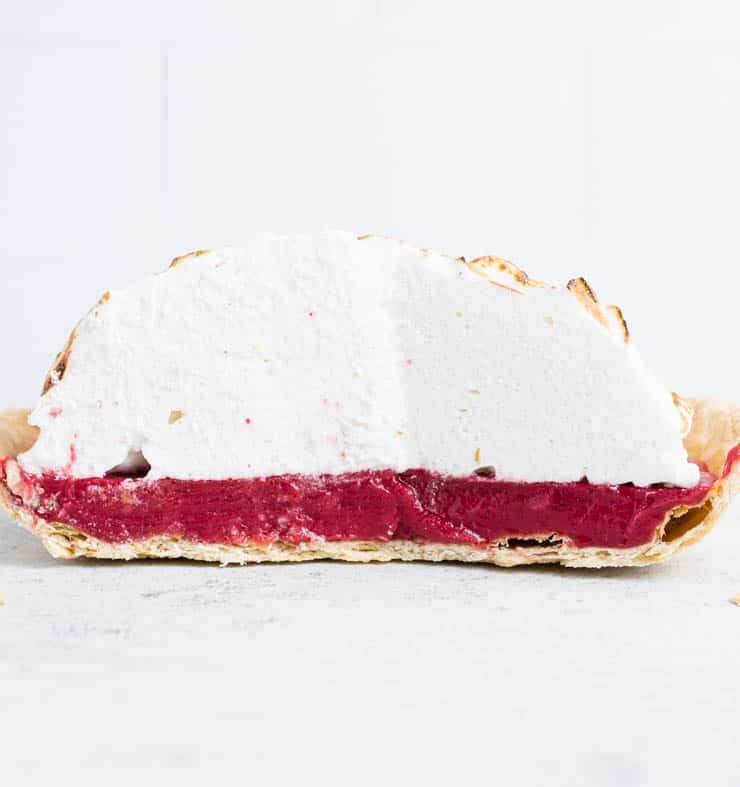 Cranberry meringue pie cut in half to show the flakiness of the pie crust.