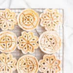 Powdered sugar dusted rosettes on a gold cooling rack.