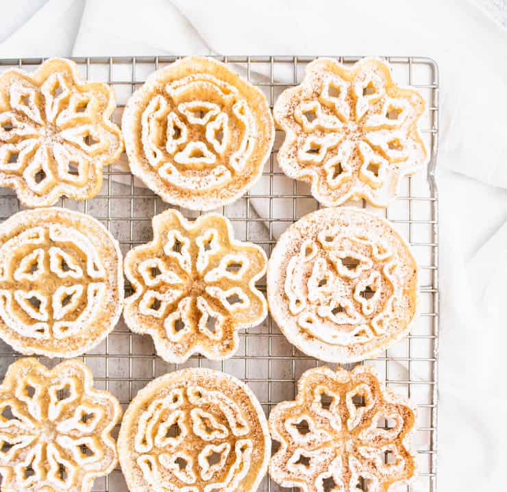 Powdered sugar dusted rosettes on a gold cooling rack.