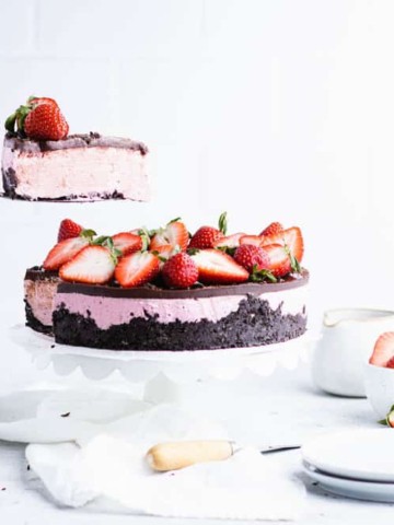 chocolate strawberry cheesecake with a slice being lifted out of it from the left.