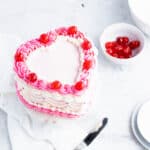 Overhead view of a pink heart shaped cake with vintage buttercream embellishments.