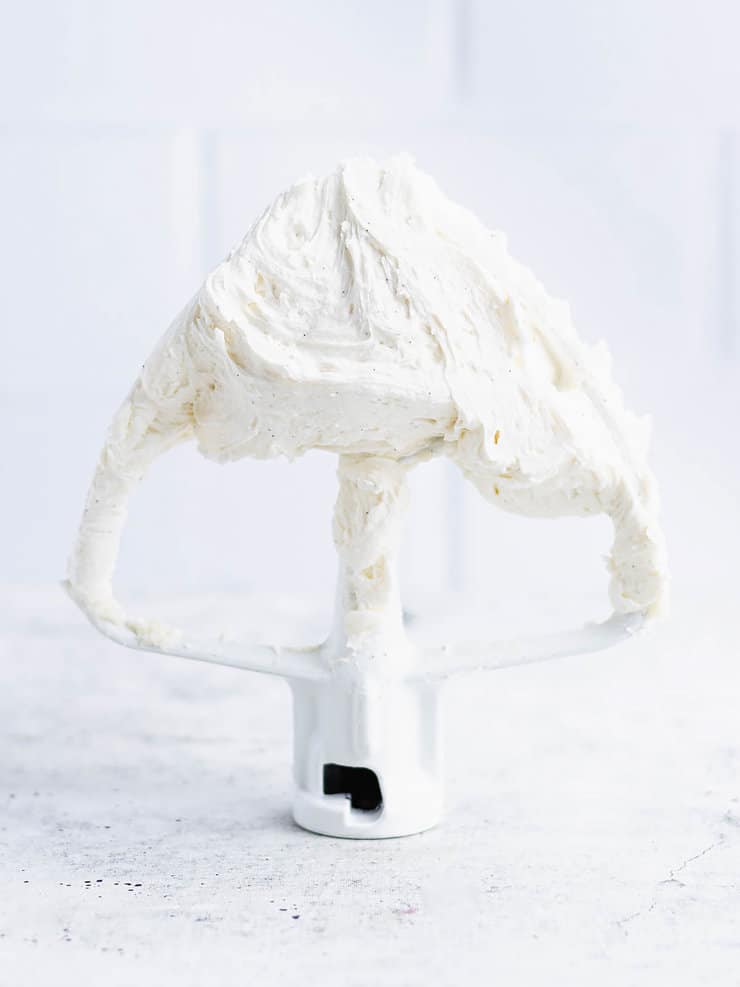 Close up of vanilla bean frosting on a white stand mixer paddle.