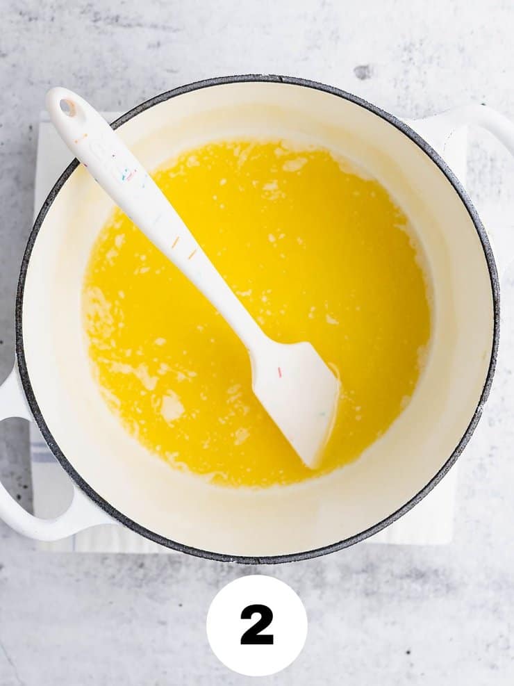 Overhead view of melted butter with a white spatula in a white pot.