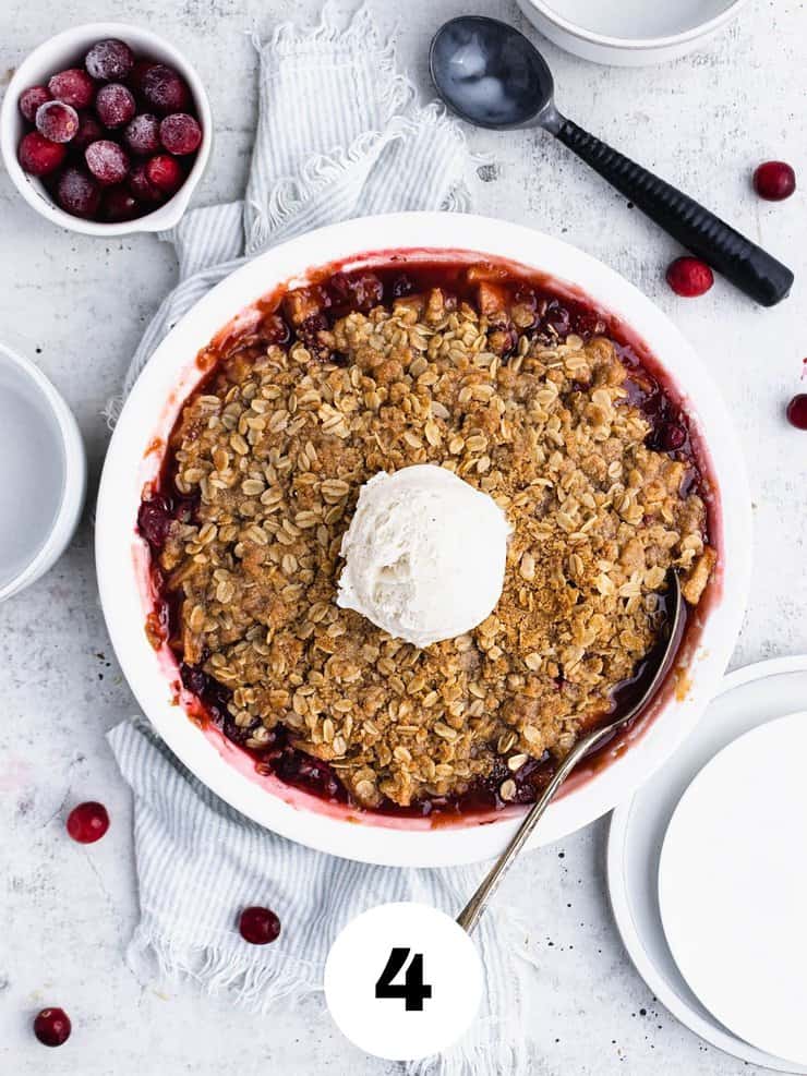 Overhead view of cranberry apple crisp with a scoop of vanilla ice cream in the center.